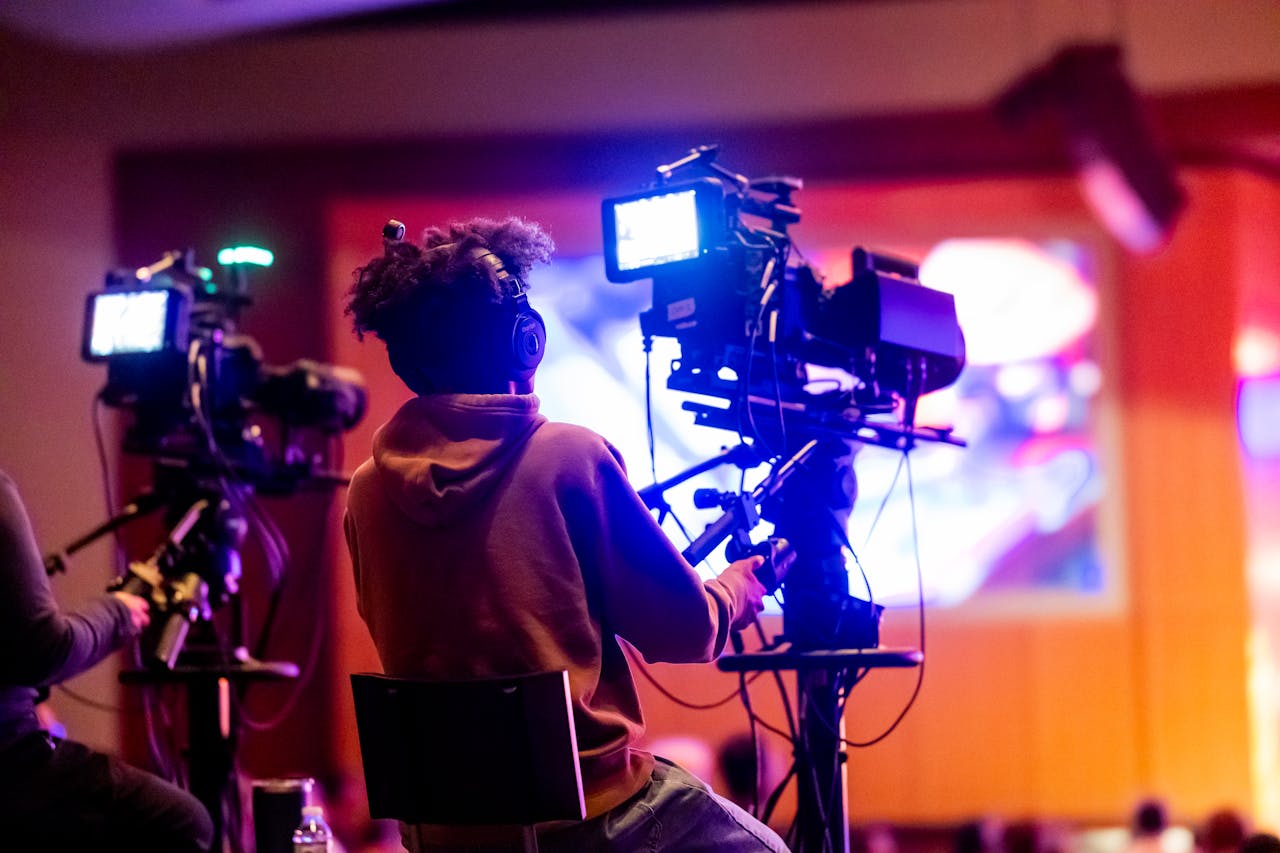 testimonials-img Back view of a videographer operating a camera at a live event, focusing on a vibrant indoor setup.