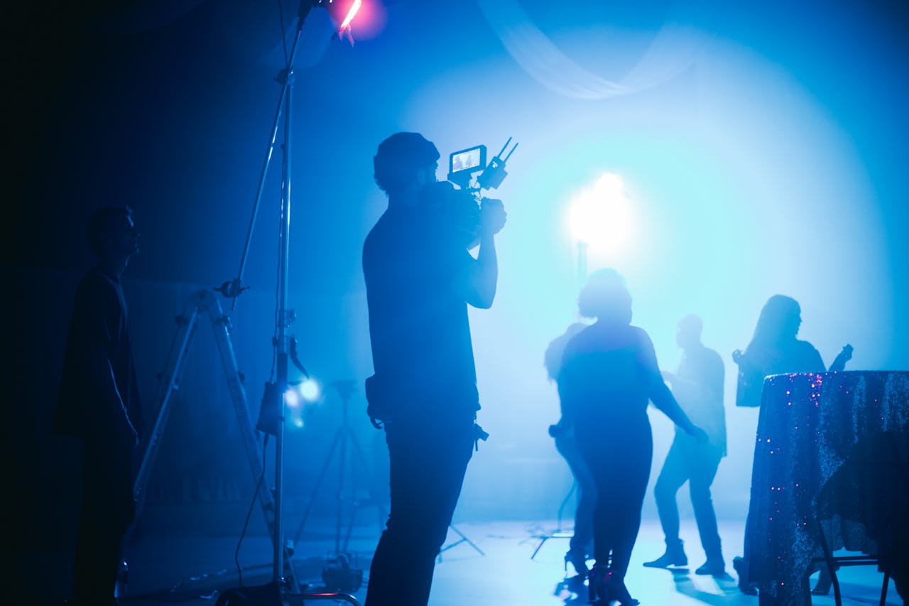 home-services-02 Cinematic night scene showcasing filming crew and silhouetted performers in vibrant light.